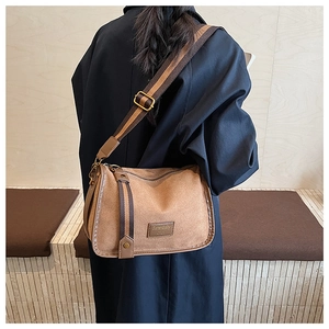 Detail of brown suede crossbody bag with vintage bronze hardware and striped strap