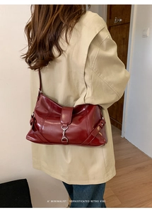 Detail of burgundy patent leather bag showing silver buckle and retro minimalist texture
