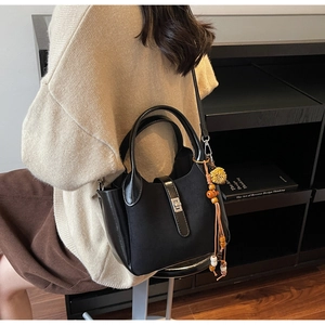 Detail of vintage black matte bucket bag with metallic twist lock and tassel charm