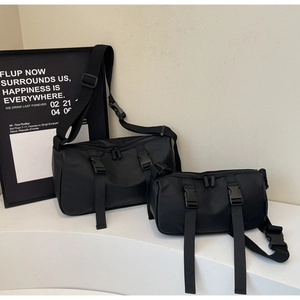 Comparison of large and small black nylon crossbody bags on a white geometric stand