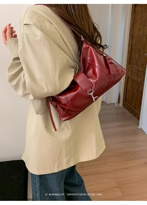 Dettaglio di borsa baguette bordeaux lucida indossata da modella in stile retrò