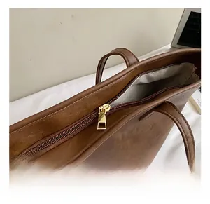 Close-up of golden metal zipper and textured brown leather on a minimalist tote bag
