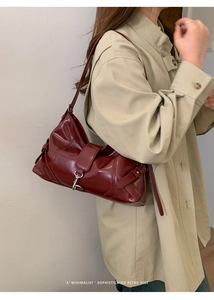 Close-up of a burgundy glossy leather shoulder bag with a metallic buckle detail