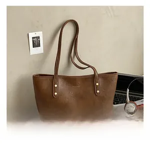 Brown vintage leather tote bag with embossed logo on an office desk with laptop