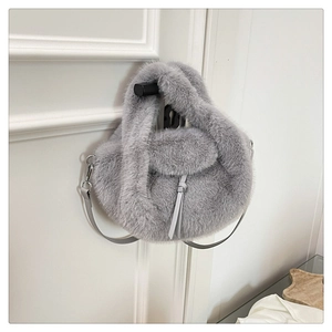 Close-up of a plush light grey faux fur handbag with a slim leather shoulder strap