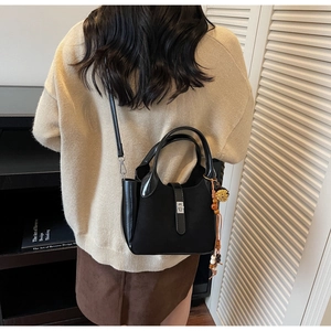 Detailed view of black matte leather crossbody bag with ethnic tassel and metal clasp