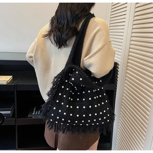 Detail of black knit tote bag featuring white pearls and decorative fringe edges