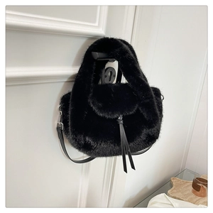 Detail view of plush black faux fur handbag with leather straps on a white door handle