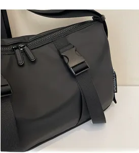 Detail of durable plastic buckle and adjustable nylon strap on a black crossbody bag