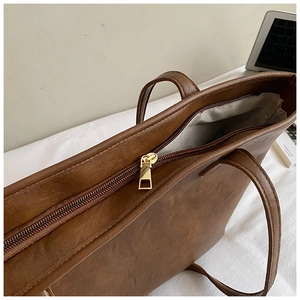 Macro detail of high-quality brown leather tote bag showing golden zipper and gray lining