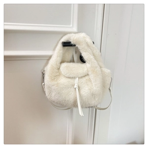 Detailed close-up of white plush handbag featuring leather lace-up and silver metal buckles