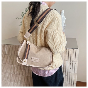 Detail of beige shoulder bag with wide striped strap and vintage square design