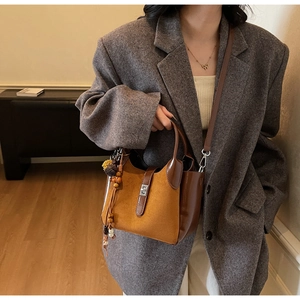 Close-up of vintage brown frosted leather bucket bag with metallic twist lock and floral charm