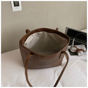 Brown PU leather tote bag with large capacity for laptop shown in lifestyle setting