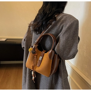 Detail of vintage matte bucket bag in caramel brown with tassel and metal buckle charms