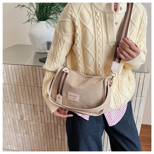 Detail of canvas Boston bag with leather trim and wide striped crossbody strap