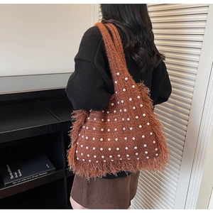 Detail of a brown knitted tote bag with white pearl beads and stylish fringe accents