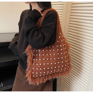 Detailed close-up of a caramel knit tote bag featuring pearl beads and long tassel fringe