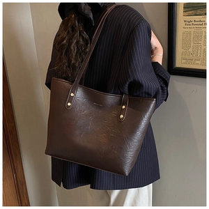 Close-up of retro brown tote bag featuring textured leather and metal rivet details