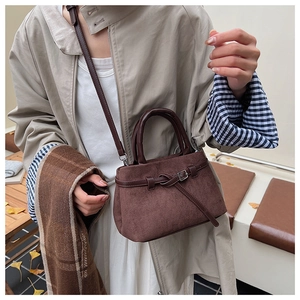 Detail of coffee brown matte bucket bag with retro buckle in an autumn outdoor setting