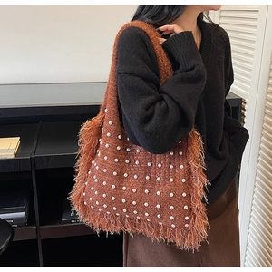 Detail of caramel knit tote bag with pearls and long side fringes on a model's shoulder
