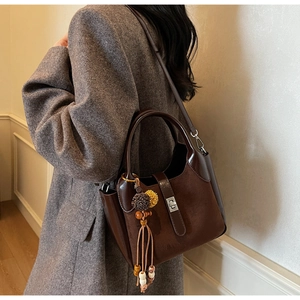 Detail of vintage brown bucket bag with matte suede texture and retro fringe charm