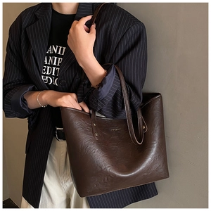 Detail view of dark coffee leather tote bag with gold rivets and hocomno brand logo