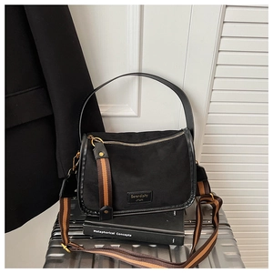 Detail of black canvas crossbody bag with vintage gold hardware and wide shoulder strap