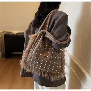 Detail of a brown knitted shoulder bag featuring white pearl accents and long tassel fringe