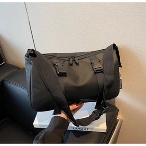 Detail of waterproof nylon crossbody bag featuring dual buckle straps and wide shoulder strap