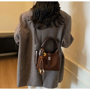 Detail of dark brown frosted bucket bag with suede texture and metallic twist lock
