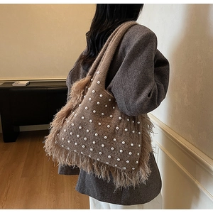 Detail of a brown knitted tote bag featuring white pearl beads and soft feather fringes