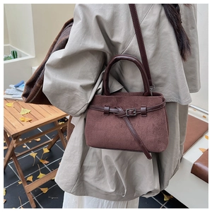 Detailed side view of a dark brown frosted bucket bag worn by a model in autumn scenery
