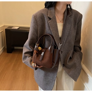 Detail of dark brown vintage bucket bag with suede texture and beaded tassel charm