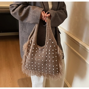 Detail of brown knit tote bag with white pearls and soft feather fringe trim