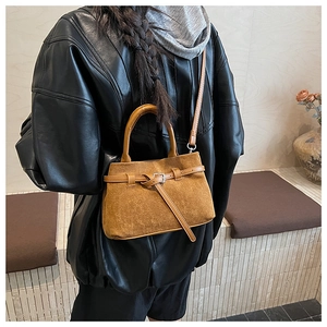 Detail of the brown frosted suede bucket bag with metallic buckle and leather straps