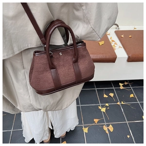 Detail of vintage dark brown suede handbag with leather trim in an autumn outdoor setting