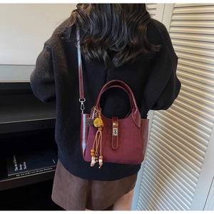 Detailed macro of burgundy bucket bag featuring matte finish and glossy leather contrast