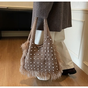 Detail of a brown knit tote bag featuring white pearl accents and soft feather trim