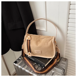 Detail of khaki suede crossbody bag with Serendipity label on a silver suitcase