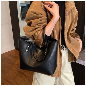 Close-up of black leather tote bag with gold HOCONU logo and shoulder strap detail