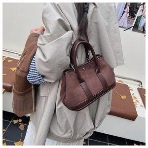 Detailed view of vintage dark brown suede handbag with leather handles and metallic buckle