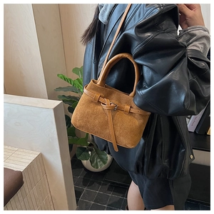 Detail of caramel brown matte leather bucket bag with metal buckle knot decoration