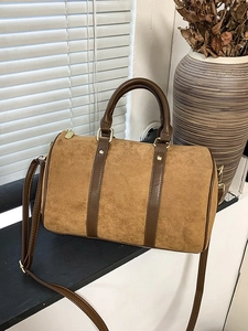 Retro brown suede Boston bag with leather handles on a windowsill in natural light