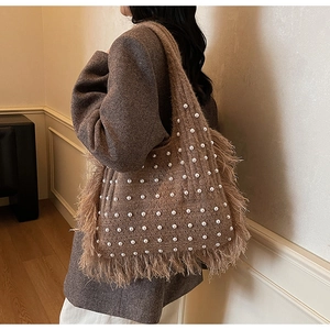 Detail of a brown knit tote bag with white pearl accents and long fringe trim side view