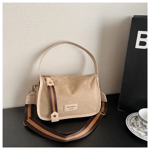 Detail of khaki suede crossbody bag with colorful striped wide strap and logo patch
