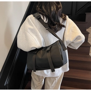 Model view showing the back profile of a black nylon crossbody bag with adjustable straps