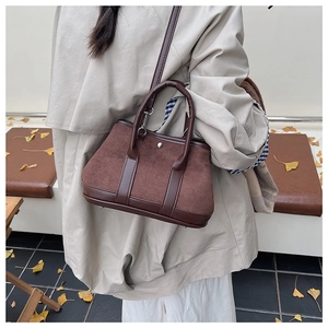 Outdoor lifestyle shot of a brown suede crossbody bag with leather trim and silver clasp