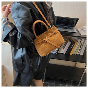 Brown suede crossbody bag worn by model in a minimalist modern office interior setting