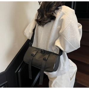 Detail view of black waterproof nylon crossbody bag with buckle straps for sports